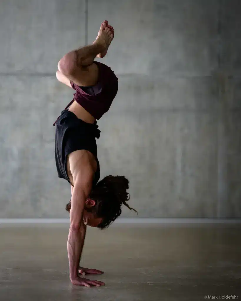 Maxime exécutant un handstand complexe pendant la formation 300 heures.